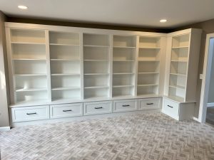 Wall-to-wall custom built-in bookcase with open shelving and lower cabinet drawers in a Brookwood home in Fort Wayne, Indiana