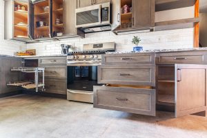 Custom kitchen cabinetry featuring pull-out shelves, open cabinets, and smart storage solutions around stainless steel appliances in a Brookwood home in Fort Wayne, Indiana