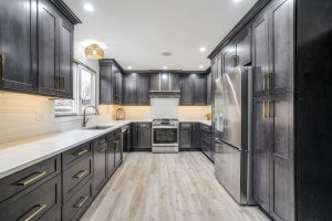 Custom luxury kitchen with dark wood cabinetry, gold hardware, stainless steel appliances, and quartz countertops in a Brookwood home in Fort Wayne, Indiana