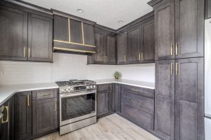 Custom modern kitchen with dark wood cabinetry, gold hardware, and built-in range in a Brookwood home in Fort Wayne, Indiana