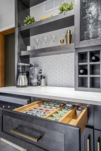 Custom coffee and beverage station featuring a K-cup storage drawer, built-in wine rack, open shelves, and glass-front cabinets in a Brookwood home in Fort Wayne, Indiana