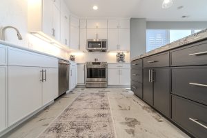 Custom modern kitchen with white upper cabinets, dark island cabinetry, stainless steel appliances, and quartz countertops in a Brookwood home in Fort Wayne, Indiana