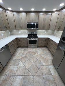 Custom U-shaped kitchen with warm wood cabinetry, stainless steel appliances, quartz countertops, and tile flooring in a Brookwood home in Fort Wayne, Indiana