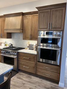 Custom kitchen with warm wood cabinetry, granite countertops, stainless steel appliances, and double oven in a Brookwood home in Fort Wayne, Indiana